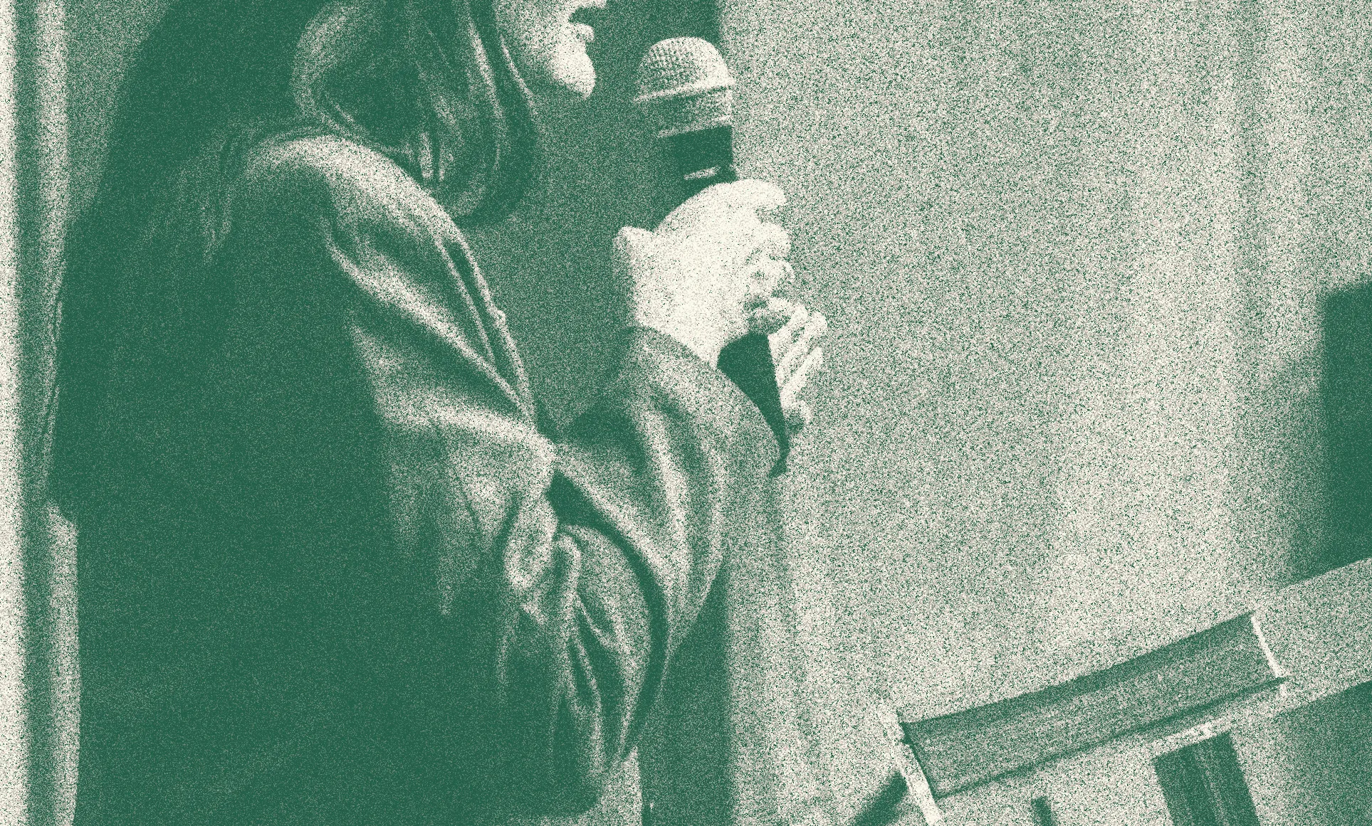 Grainy green photo of a singer holding a microphone
